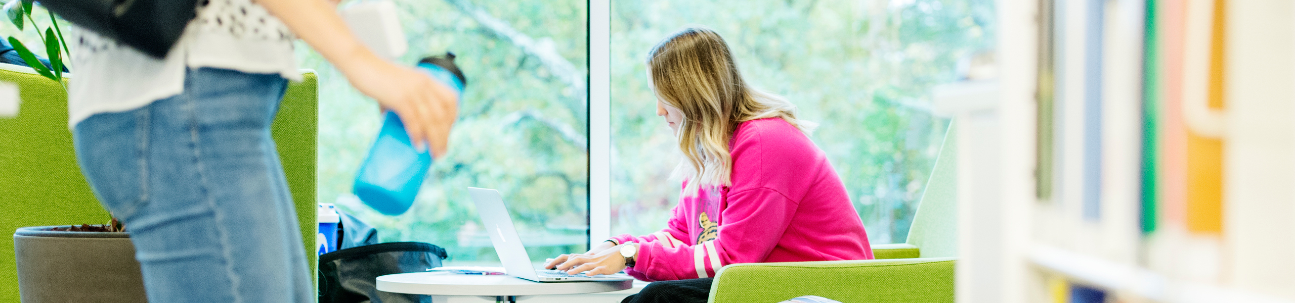 Kvinnlig student sitter vid dator i GIH:s bibliotek