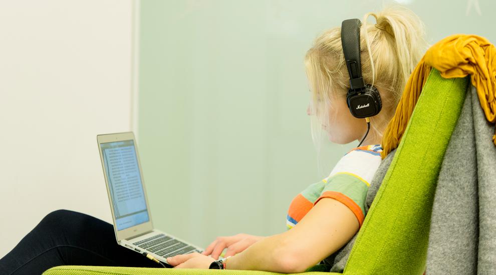 Kvinnlig student med hörlurar och laptop
